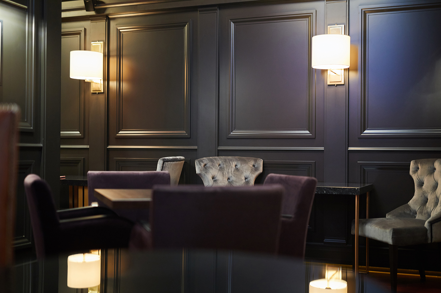 Luxurious restaurant Lamps along black wooden walls, tables and armchairs for guests of luxurious restaurant